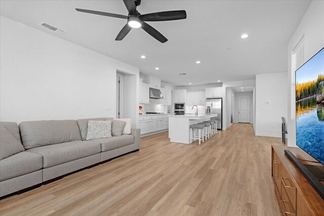 living room with ceiling fan, sink, and light hardwood / wood-style floors