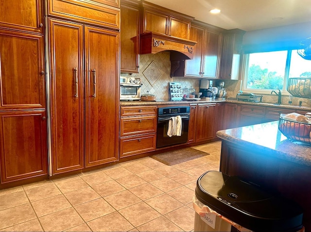 kitchen featuring stone counters, light tile patterned flooring, black oven, backsplash, and custom exhaust hood