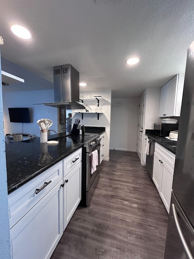 kitchen featuring island exhaust hood, appliances with stainless steel finishes, dark wood-type flooring, dark stone counters, and white cabinets