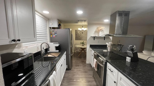 kitchen featuring appliances with stainless steel finishes, ventilation hood, a sink, wood finished floors, and a chandelier
