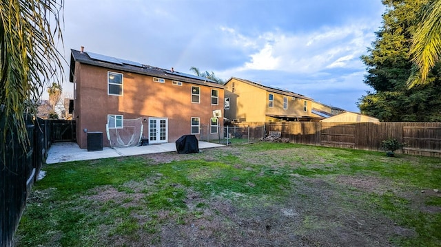 back of property featuring central AC, a patio area, solar panels, and a lawn