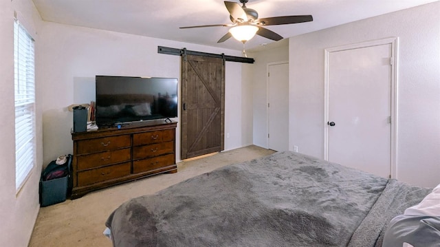 carpeted bedroom featuring ceiling fan and a barn door