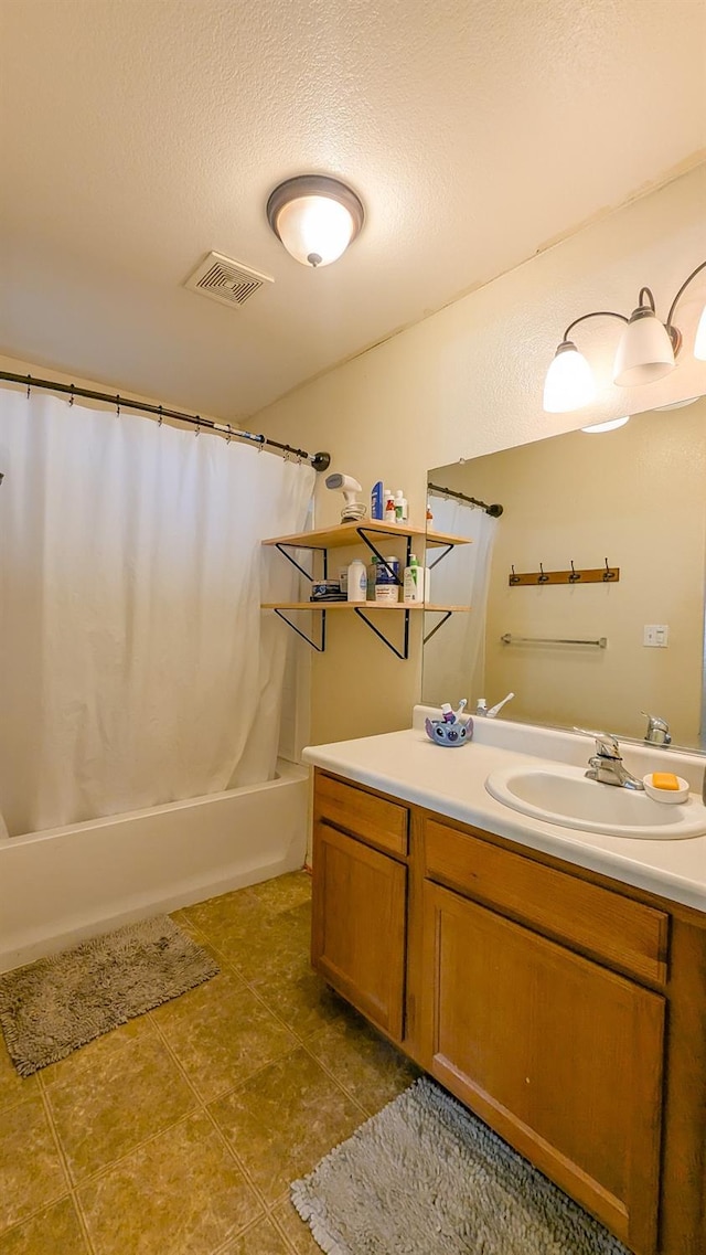 bathroom featuring tile patterned flooring, vanity, shower / tub combo, and a textured ceiling