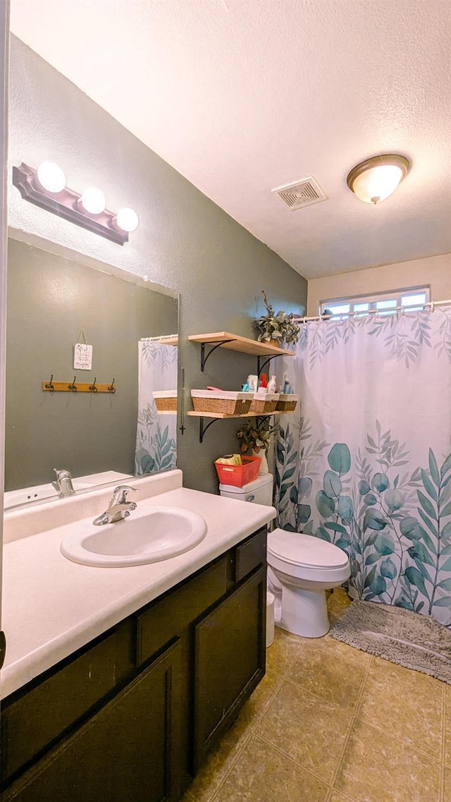 bathroom featuring vanity, tile patterned floors, toilet, and a textured ceiling