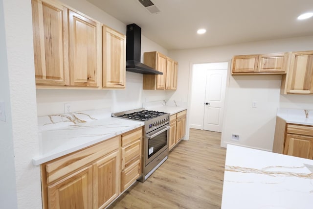 kitchen featuring light wood-type flooring, light brown cabinetry, stainless steel stove, and wall chimney range hood