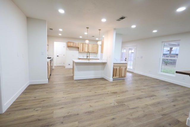 kitchen featuring sink, hanging light fixtures, light brown cabinets, light hardwood / wood-style flooring, and kitchen peninsula