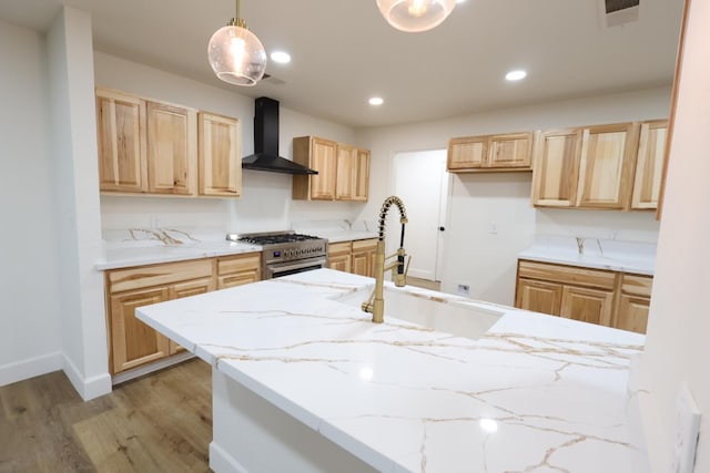 kitchen with decorative light fixtures, sink, high end stainless steel range oven, light hardwood / wood-style floors, and wall chimney range hood