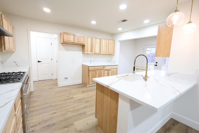 kitchen featuring sink, stainless steel stove, hanging light fixtures, and light brown cabinets