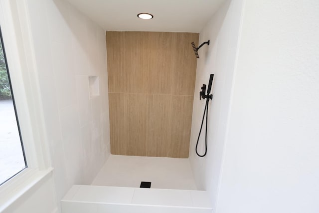 bathroom with tiled shower and plenty of natural light