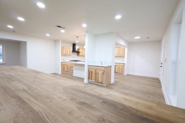 kitchen with pendant lighting, light brown cabinetry, light hardwood / wood-style floors, and wall chimney exhaust hood