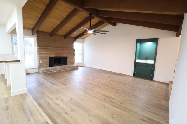 unfurnished living room with sink, light hardwood / wood-style flooring, a fireplace, lofted ceiling with beams, and wooden ceiling