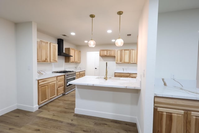 kitchen featuring wall chimney exhaust hood, sink, decorative light fixtures, light wood-type flooring, and high end stainless steel range oven