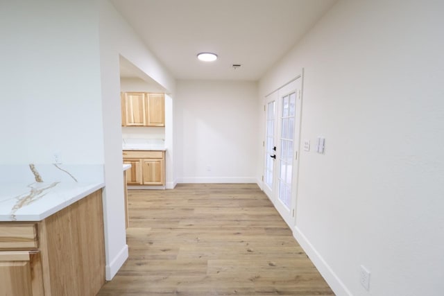 hallway with french doors and light hardwood / wood-style flooring