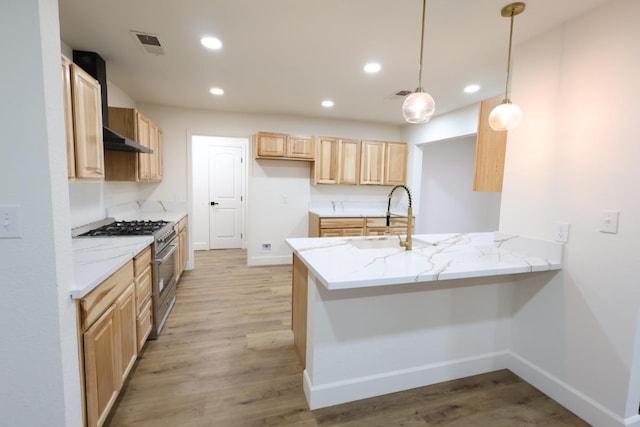 kitchen featuring sink, hanging light fixtures, kitchen peninsula, light stone countertops, and high end stove