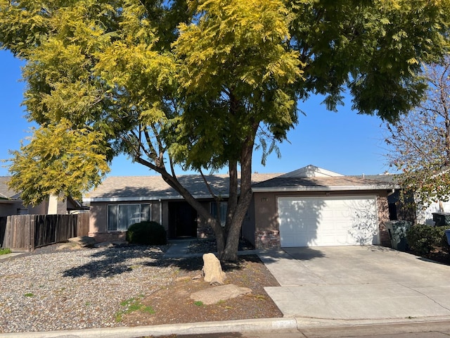 single story home with a garage, concrete driveway, and fence