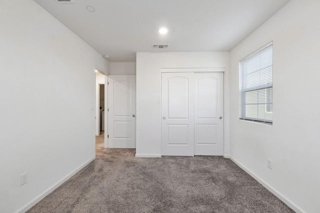 unfurnished bedroom with light carpet and a closet