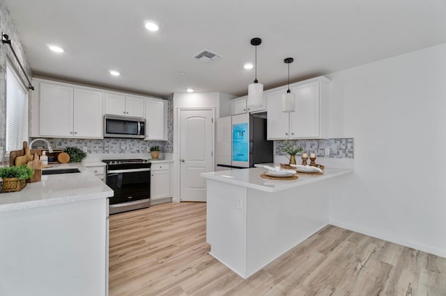 kitchen featuring appliances with stainless steel finishes, pendant lighting, white cabinetry, sink, and light wood-type flooring