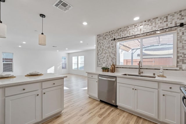 kitchen featuring pendant lighting, sink, white cabinets, backsplash, and stainless steel dishwasher