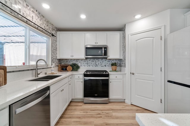 kitchen featuring sink, stainless steel appliances, white cabinets, and light wood-type flooring