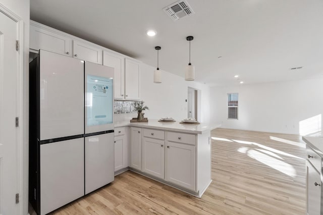 kitchen featuring kitchen peninsula, white cabinets, and refrigerator