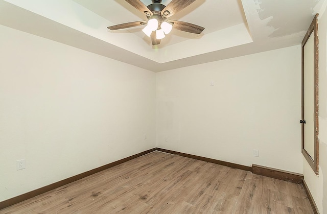 unfurnished room with a tray ceiling, light hardwood / wood-style flooring, and ceiling fan