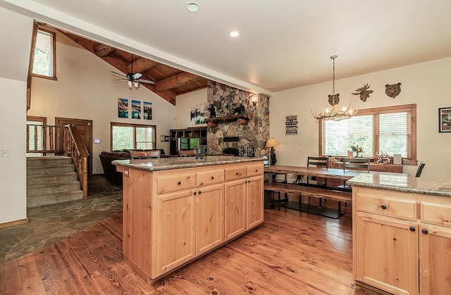 kitchen with beam ceiling, hanging light fixtures, hardwood / wood-style flooring, and light brown cabinetry