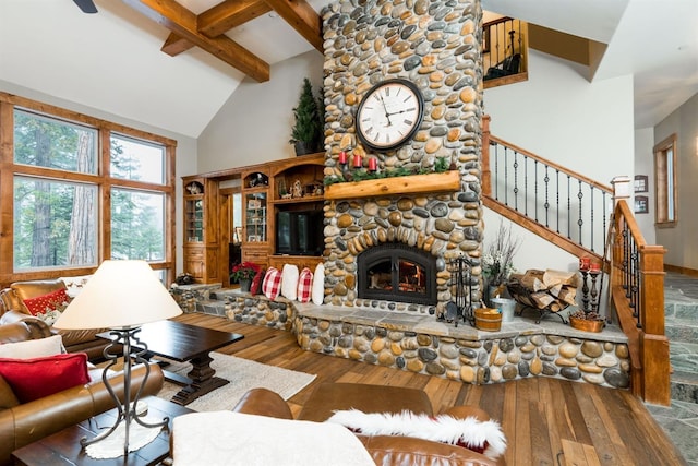 living room featuring wood-type flooring, a stone fireplace, high vaulted ceiling, and beam ceiling