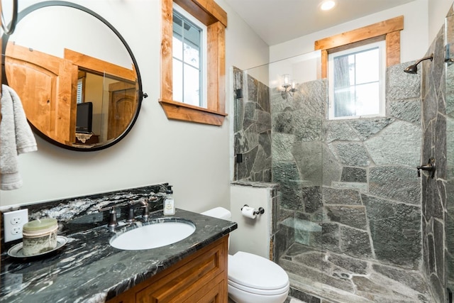 bathroom featuring vanity, a tile shower, and toilet