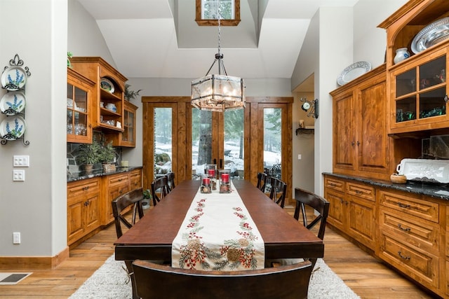 dining room featuring lofted ceiling, a notable chandelier, and light wood-type flooring