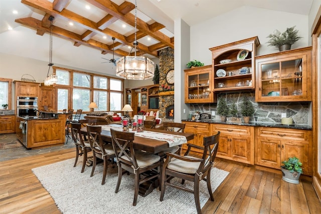 dining area featuring coffered ceiling, high vaulted ceiling, light hardwood / wood-style flooring, beam ceiling, and ceiling fan with notable chandelier