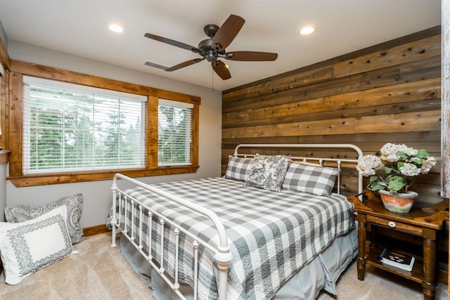 bedroom featuring light colored carpet, ceiling fan, and wood walls