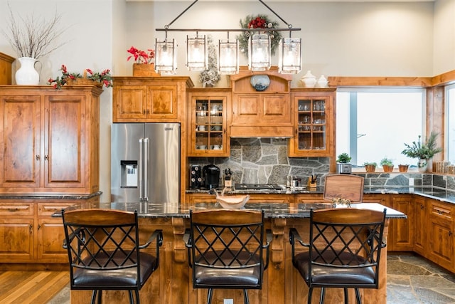 kitchen featuring tasteful backsplash, stainless steel appliances, dark stone countertops, and a kitchen bar