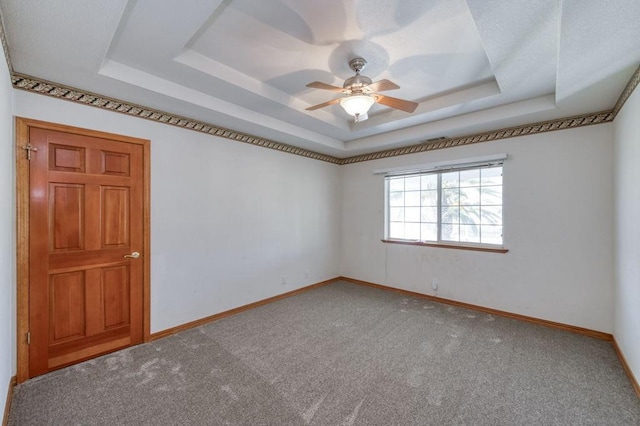 unfurnished room featuring ceiling fan, a tray ceiling, and carpet