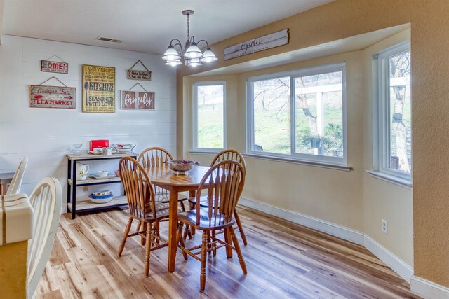 dining space with an inviting chandelier and light hardwood / wood-style floors