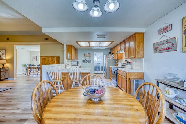 dining area with washer / clothes dryer, sink, and light wood-type flooring