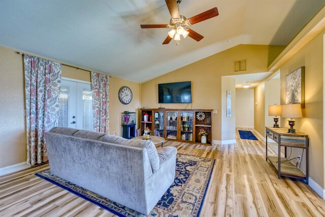 living room with vaulted ceiling, light hardwood / wood-style flooring, ceiling fan, and french doors