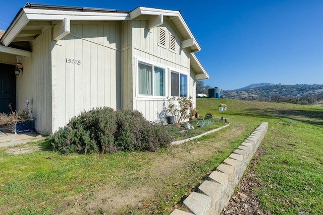 view of side of home featuring a mountain view and a yard