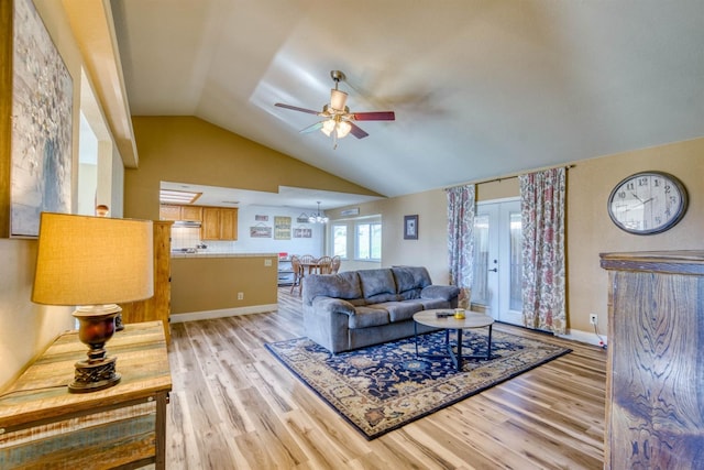 living room with french doors, lofted ceiling, ceiling fan with notable chandelier, and light hardwood / wood-style floors