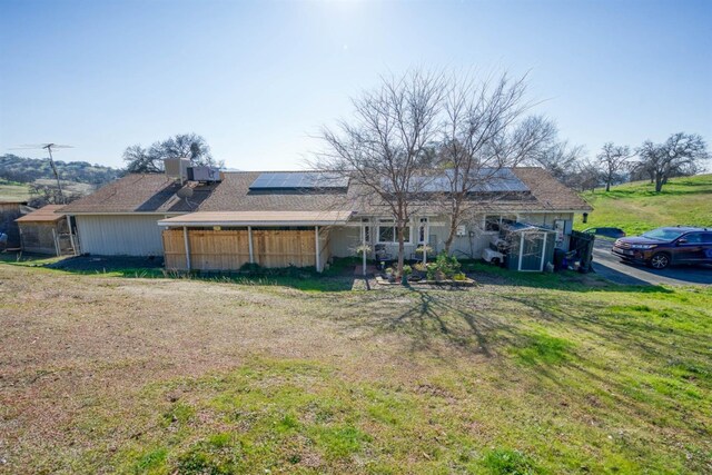 back of property featuring an outdoor structure, a yard, and solar panels