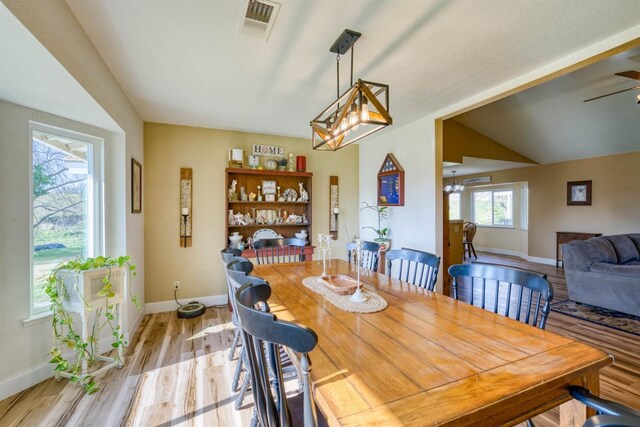 dining area with lofted ceiling, ceiling fan with notable chandelier, and light wood-type flooring