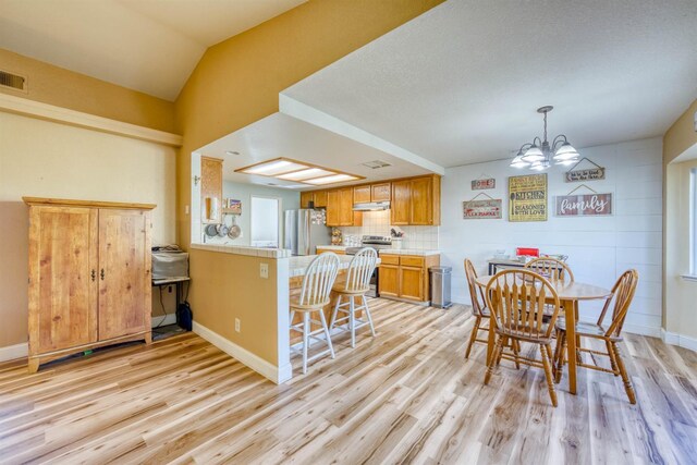 dining area with vaulted ceiling, light hardwood / wood-style floors, and a notable chandelier