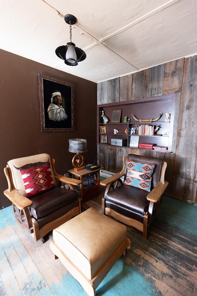 sitting room with hardwood / wood-style floors and wooden walls