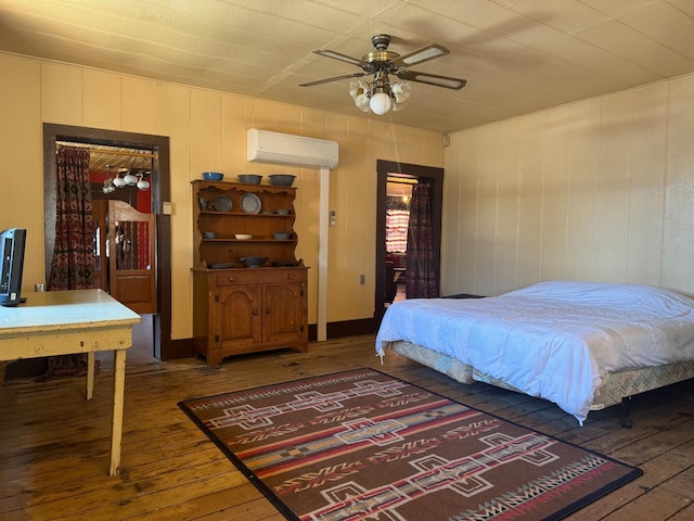 bedroom featuring dark hardwood / wood-style flooring, an AC wall unit, and ceiling fan