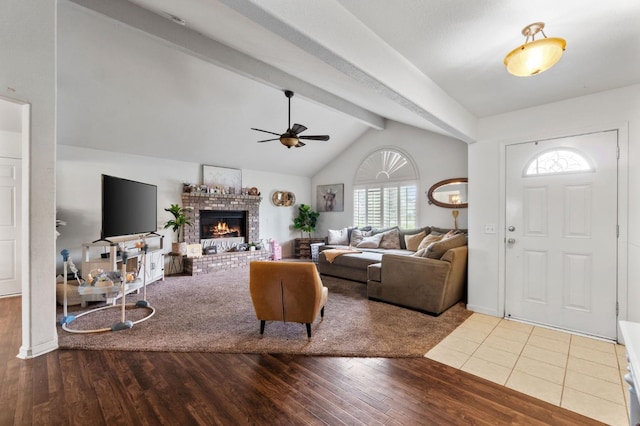 living area with wood finished floors, ceiling fan, lofted ceiling with beams, and a brick fireplace