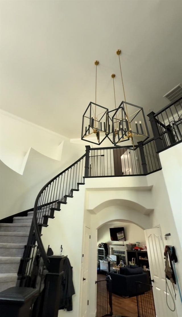 staircase with hardwood / wood-style flooring, a chandelier, and a high ceiling