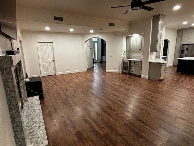 unfurnished living room with crown molding, a premium fireplace, ceiling fan, dark hardwood / wood-style floors, and beverage cooler