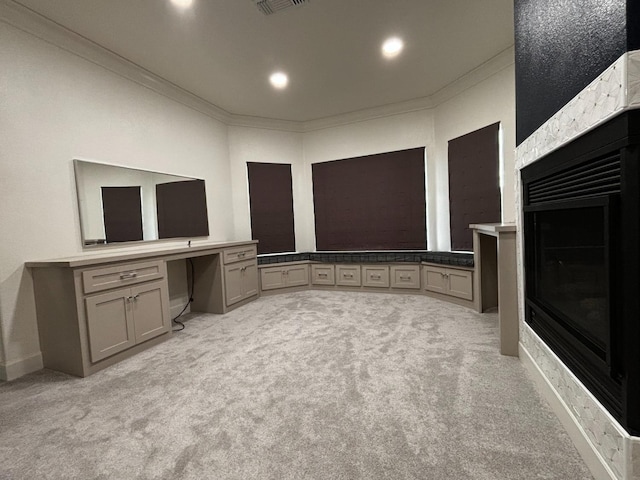 unfurnished living room featuring crown molding, light carpet, and built in desk