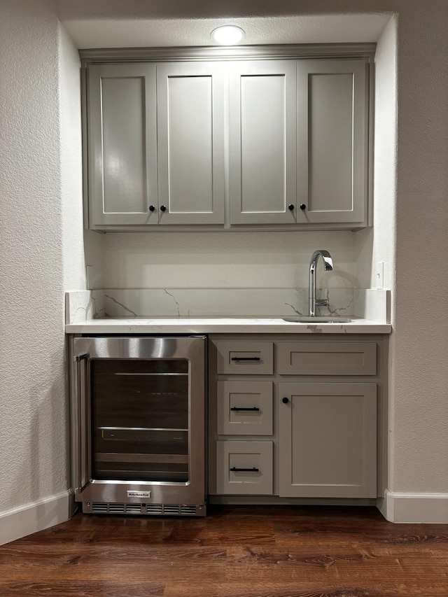 bar featuring dark hardwood / wood-style floors, beverage cooler, sink, and gray cabinetry