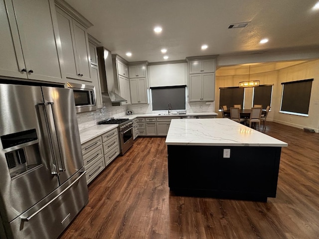 kitchen with wall chimney exhaust hood, sink, gray cabinetry, a center island, and premium appliances