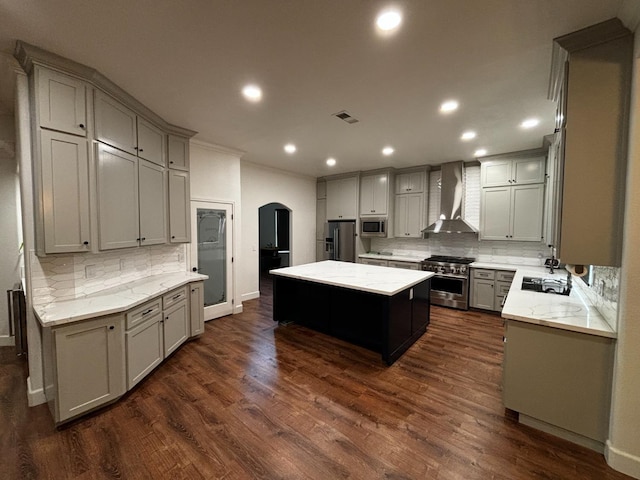 kitchen featuring gray cabinets, a center island, wall chimney exhaust hood, and appliances with stainless steel finishes